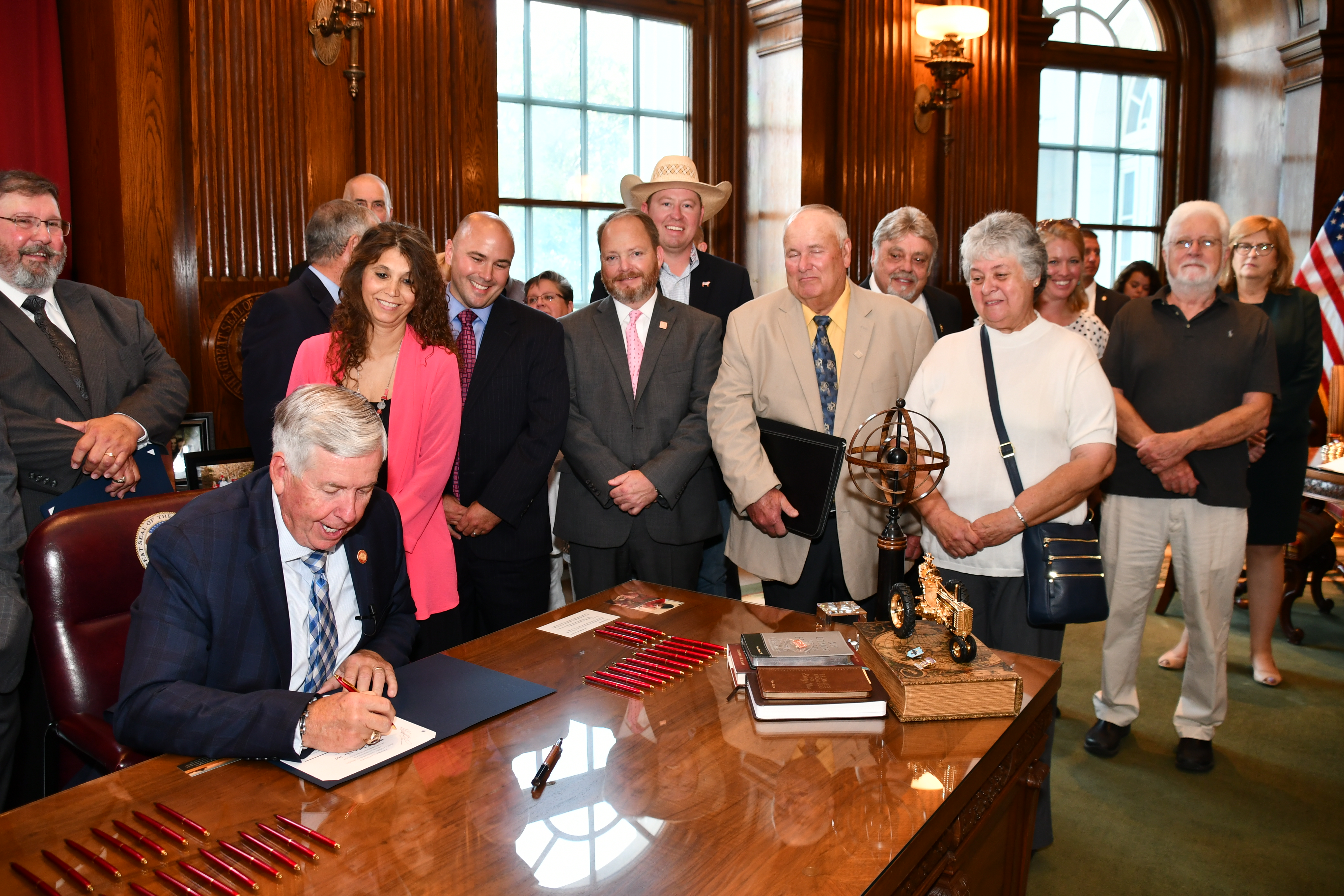 Missouri Governor Mike Parson signing House Bill 369 into law in front of a crowd.
